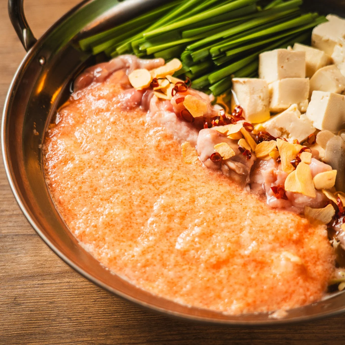 新鮮なもつ、たっぷりのニラ、豆腐、スライスされたニンニク、唐辛子が特徴的なもつ鍋