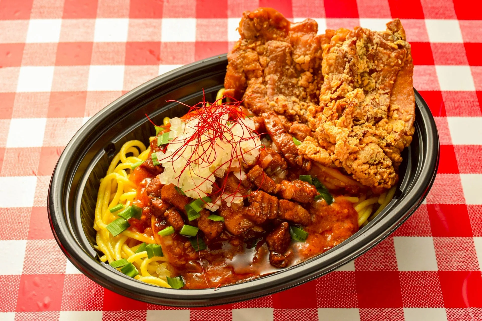 黒い容器に入った麺料理と唐揚げ