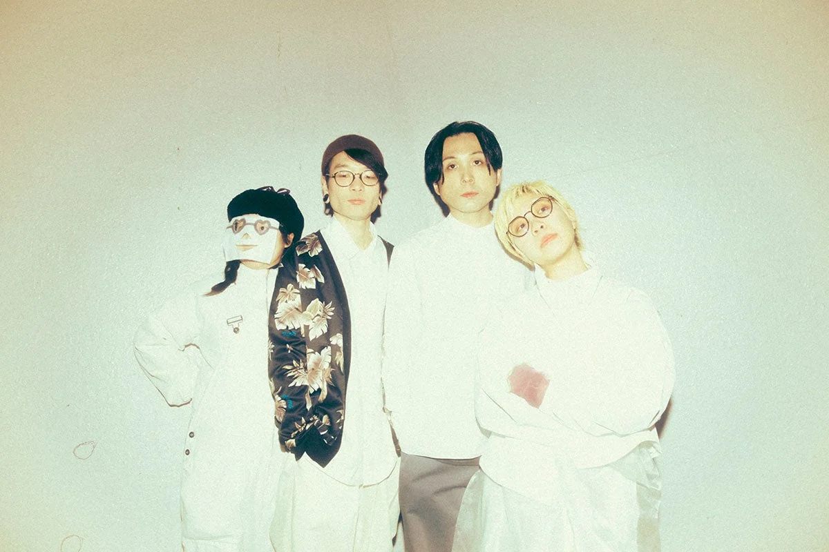 白を基調とした背景の前でポーズをとる4人組のアーティスト写真