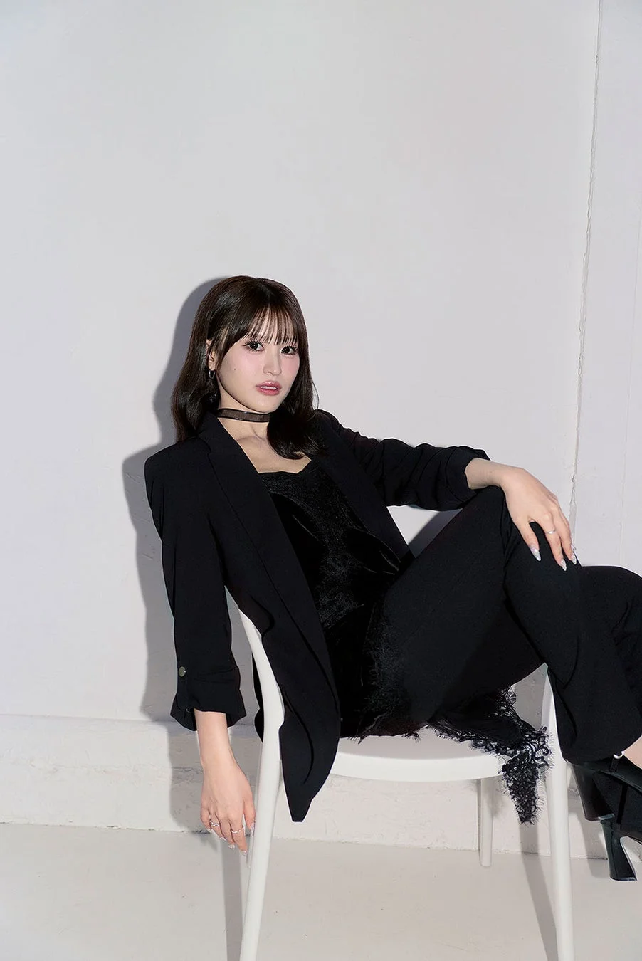 白い背景のスタジオで白い椅子に座る女性のポートレート