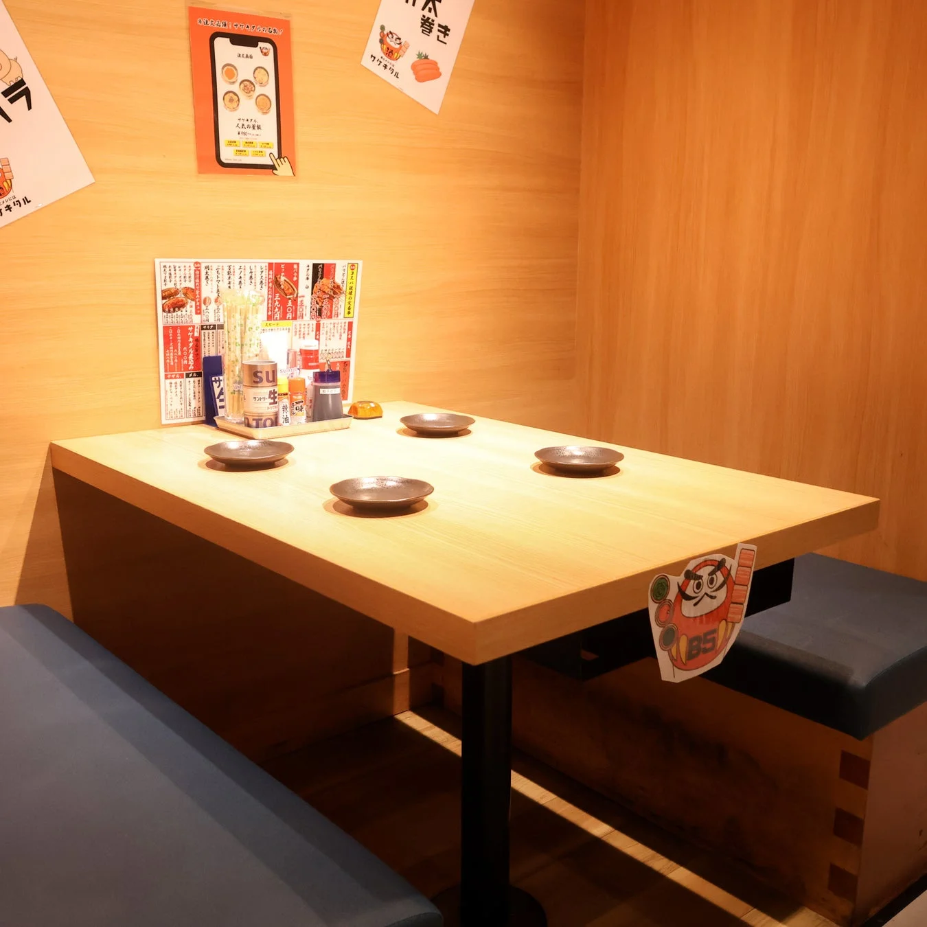 日本の居酒屋またはレストランのブース席で、木製のテーブルと青いベンチ