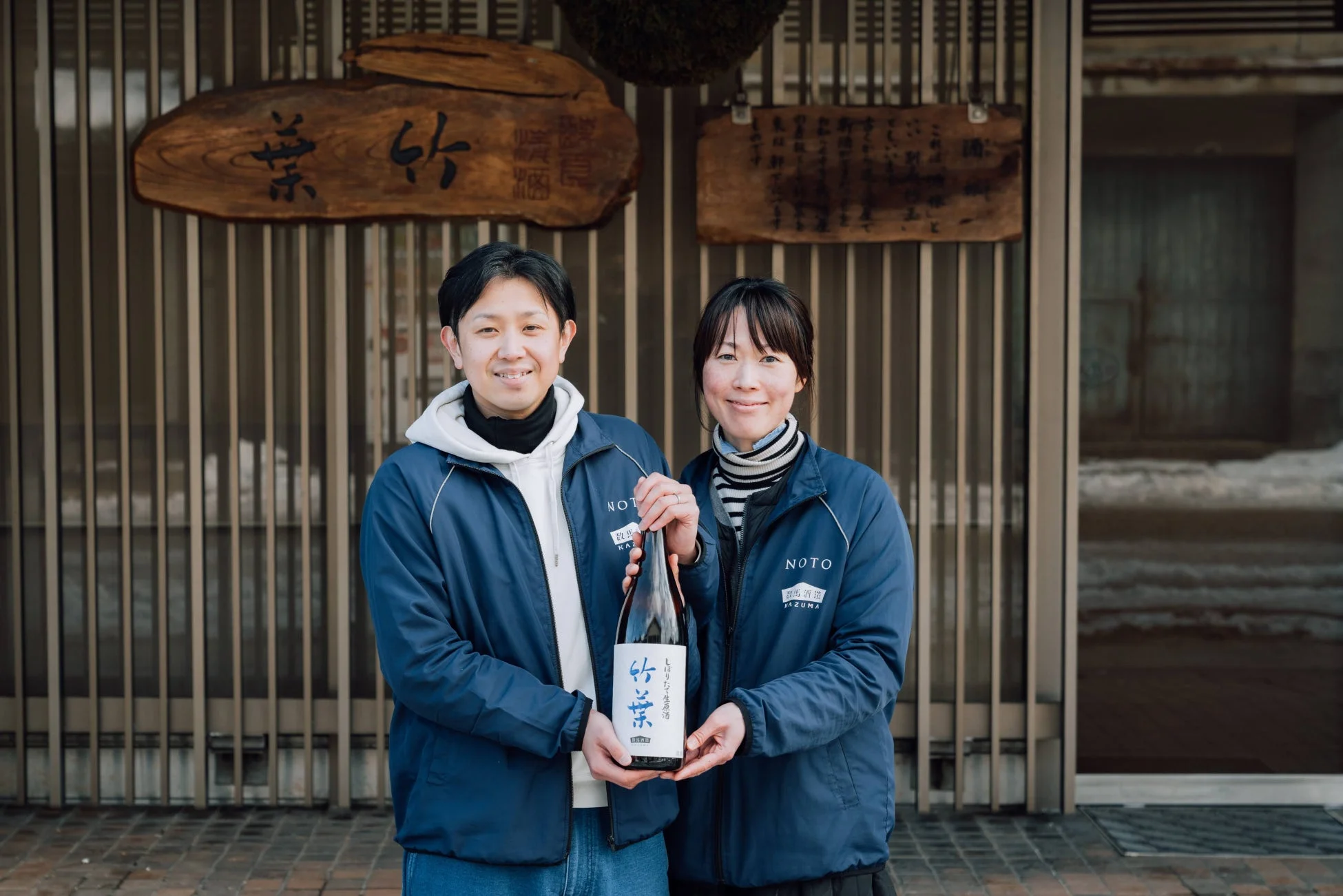 笑顔の男女二人が「竹葉」と書かれた日本酒のボトルを持っている様子