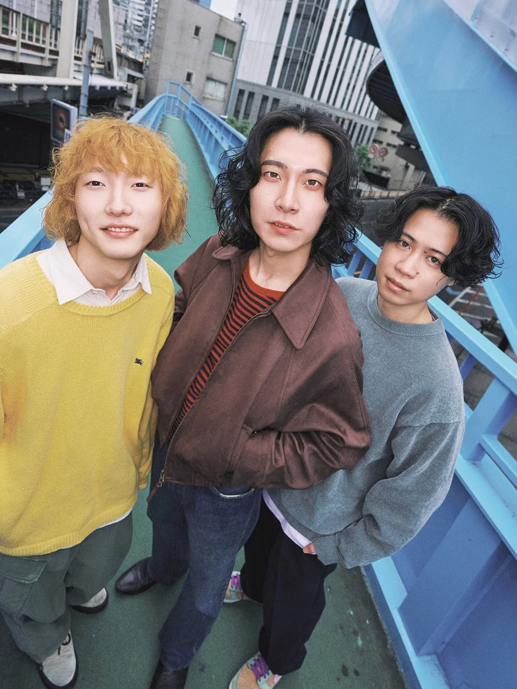青い歩道橋の上でポーズをとる3人の若者のポートレート