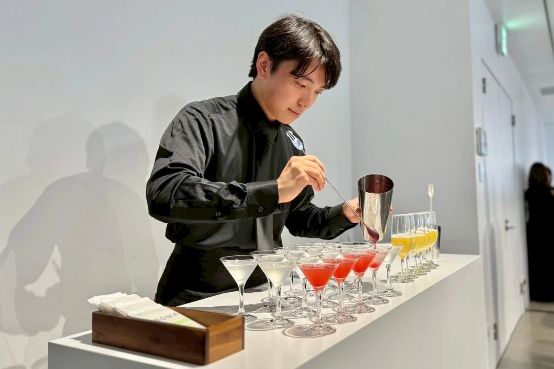黒いシャツを着た男性が、カウンターでカクテルを準備している