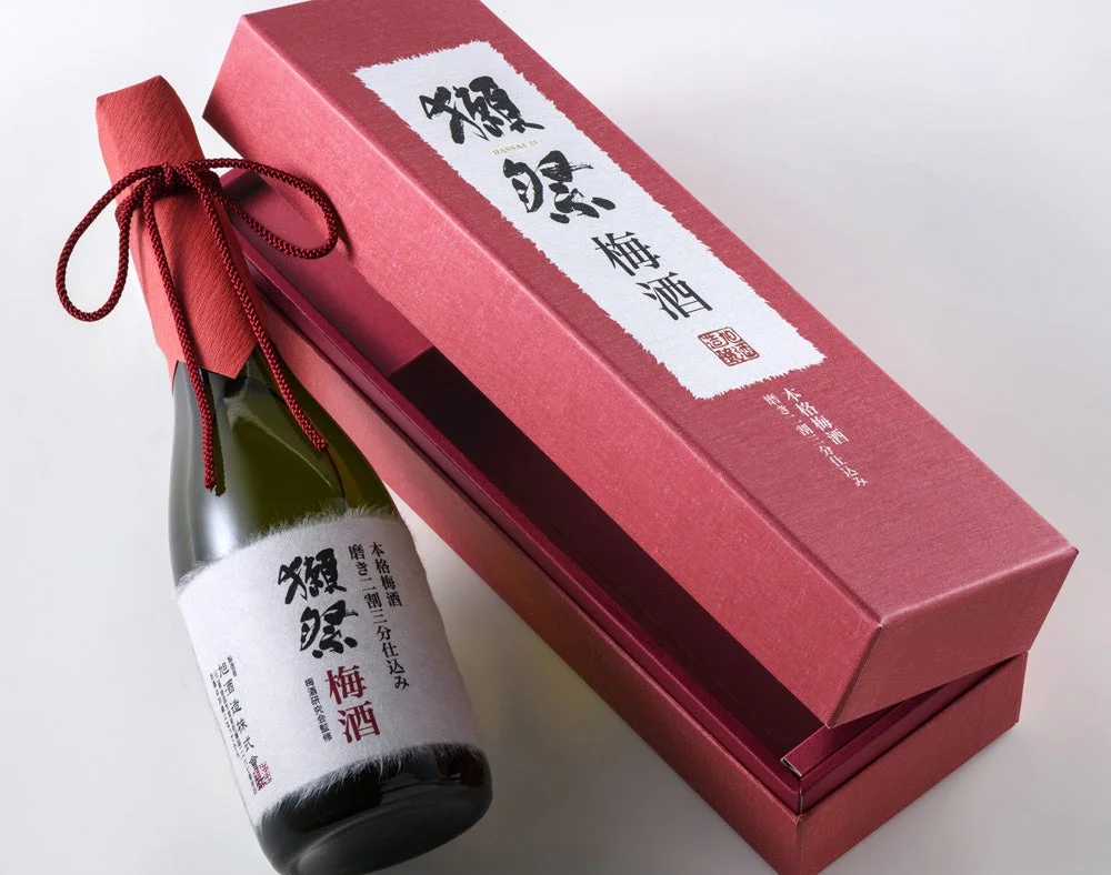 「獺祭 梅酒」のボトルと、それが入った赤い贈答用の箱が写っています。