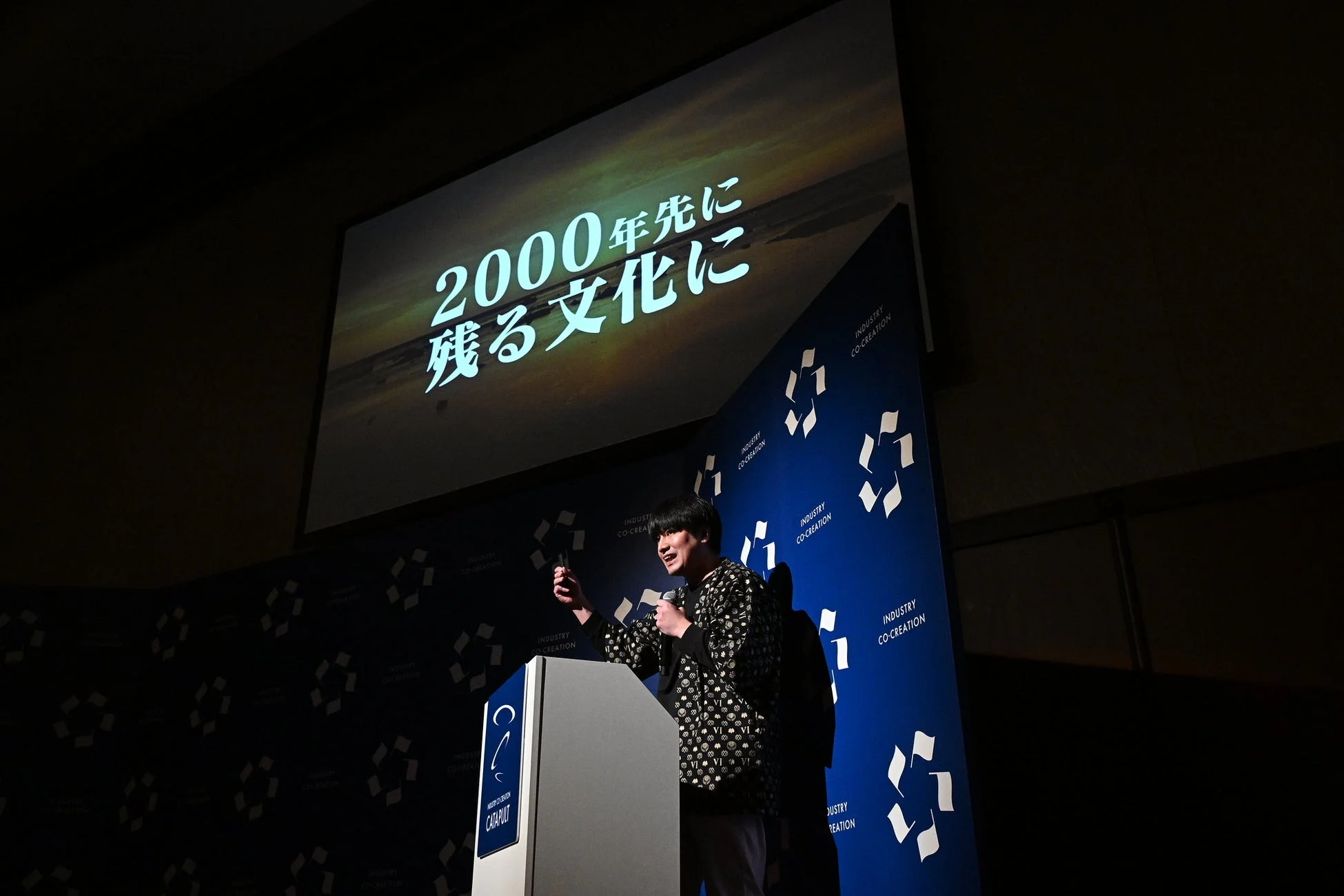 「2000年先に残る文化に」というメッセージが映し出されたスクリーン