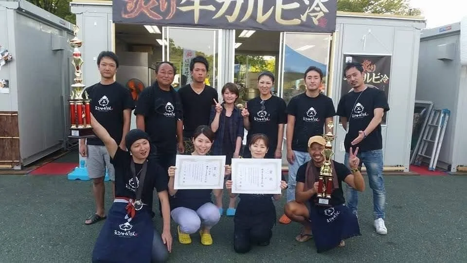 フードイベントで受賞し、トロフィーと賞状を持つ「えびすやうどん」のチーム