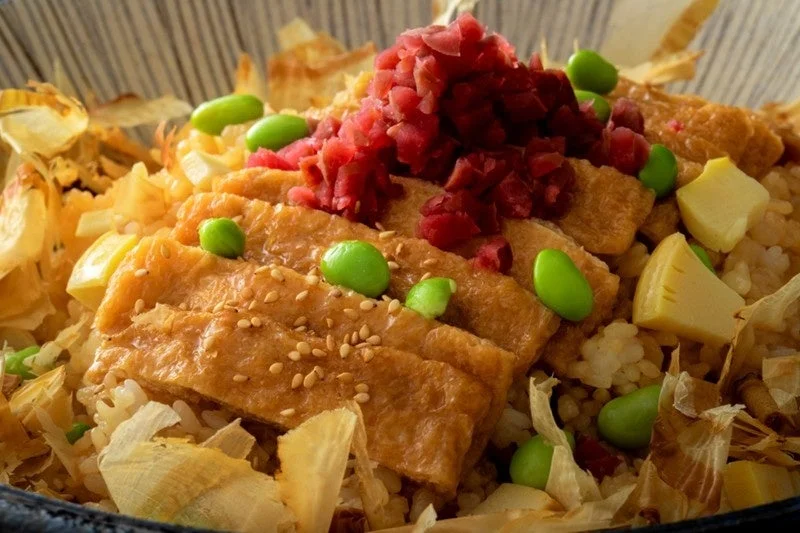 ご飯の上に甘辛く煮た油揚げ、枝豆、紅生姜、鰹節が盛り付けられた丼物