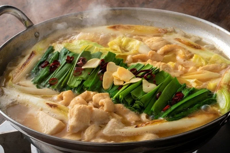 湯気が立ち上る熱々の鍋料理で、新鮮なもつ、ニラ、キャベツ、ニンニク、唐辛子がたっぷり入ったもつ鍋
