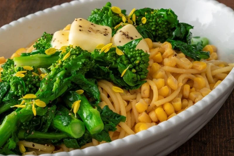 菜の花、コーン、チーズがトッピングされたパスタ料理