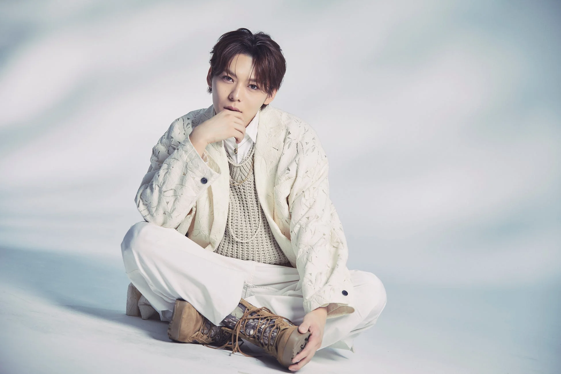 白い背景で座ってポーズをとるYOSUKE氏