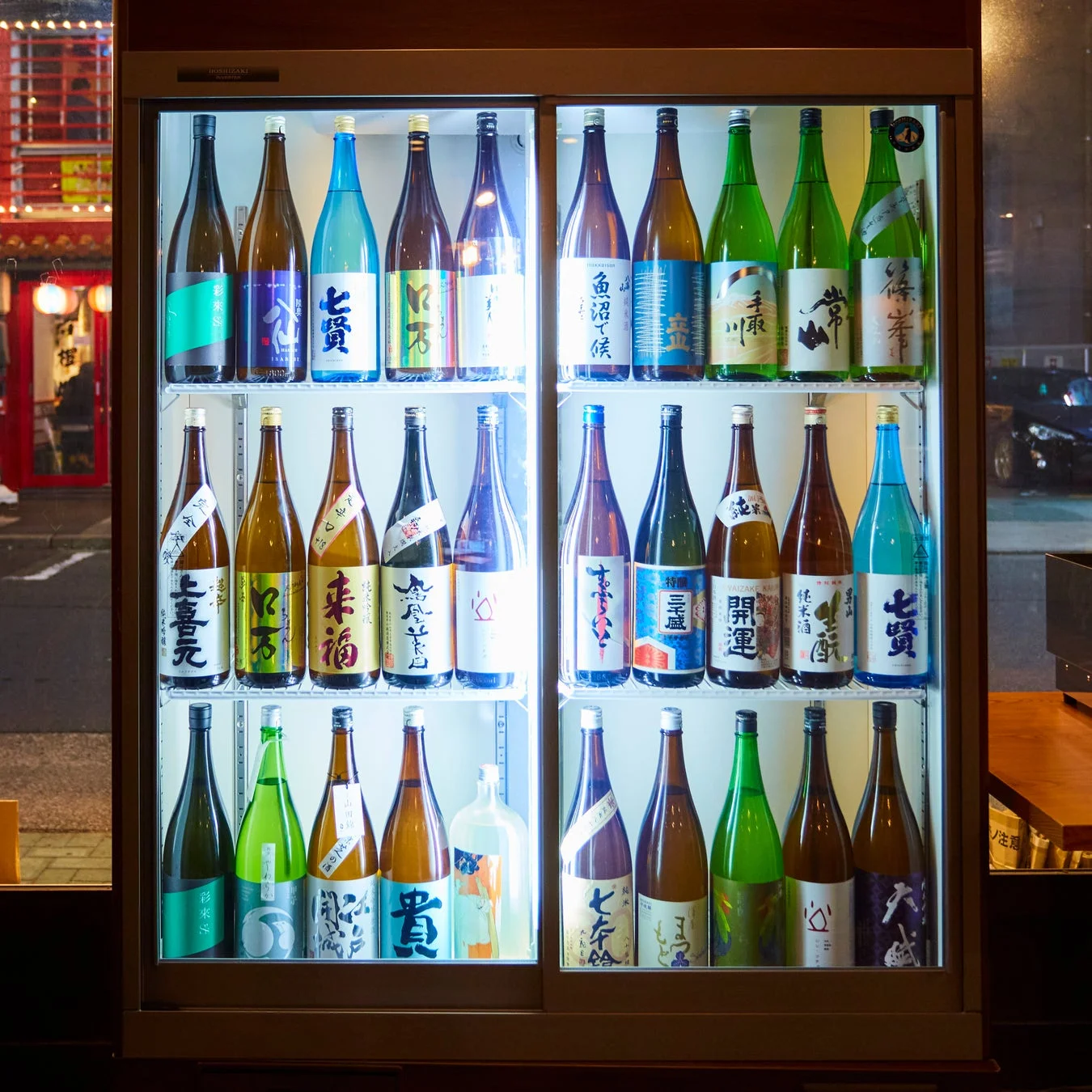 様々な日本酒のボトルが並べられた冷蔵ショーケース