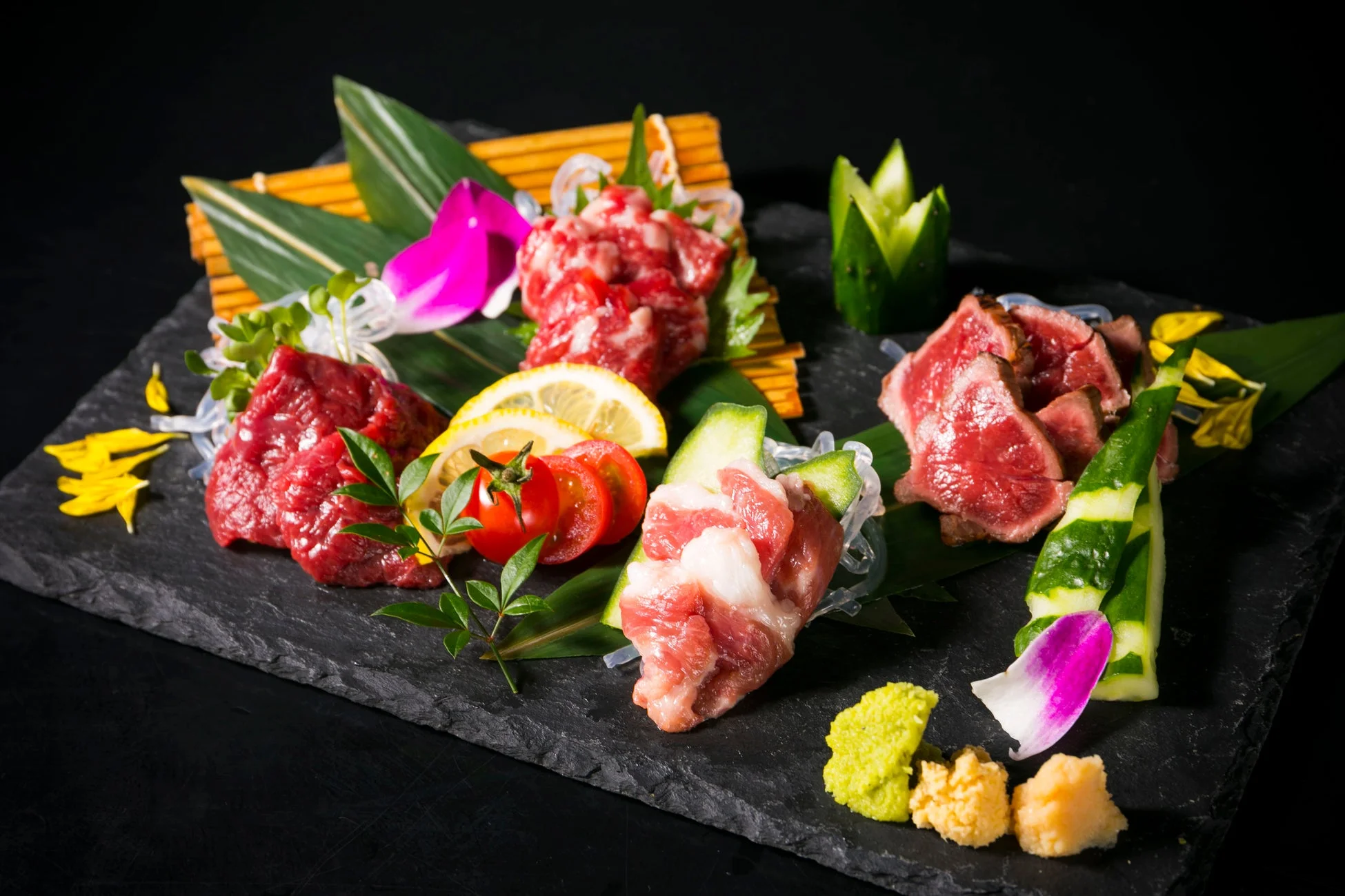 黒い石皿に盛り付けられた様々な種類の生肉料理