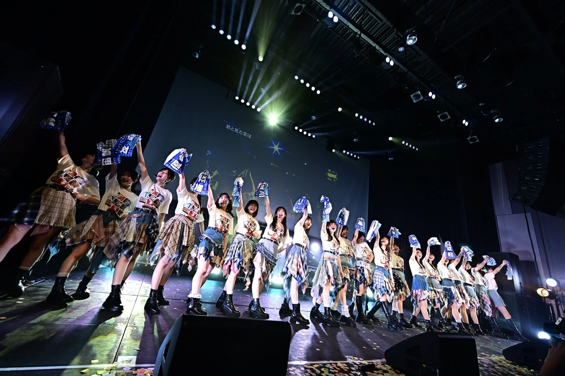 ステージでタオルを掲げパフォーマンスするメンバー