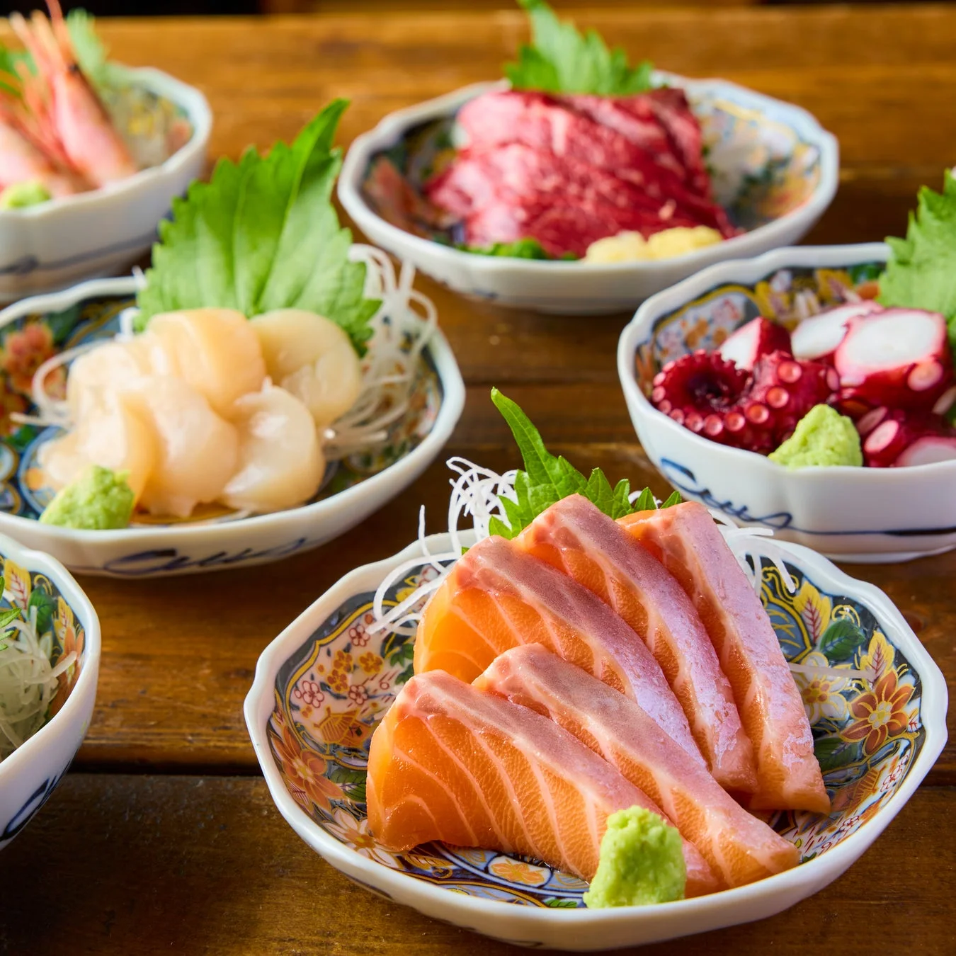 新鮮な海の幸が美しく盛り付けられた複数の刺身料理が木製のテーブルに並んでいます