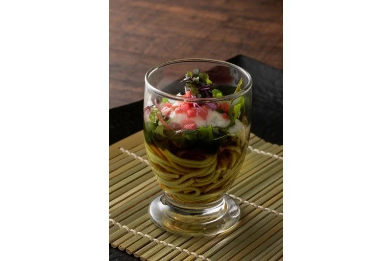 透明なグラスに盛り付けられた、涼しげな冷製麺料理