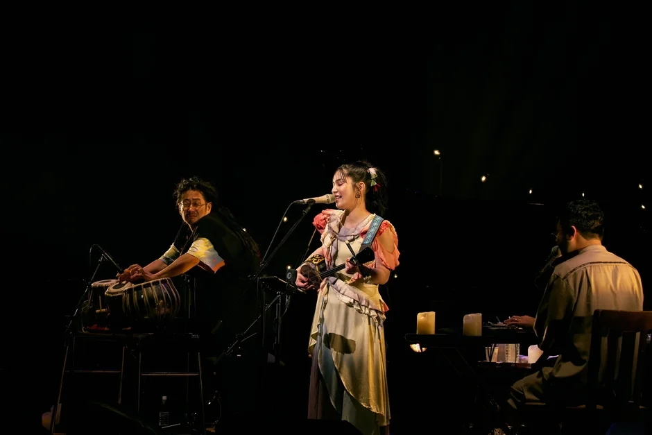 暗いステージで3人のミュージシャンが演奏しているライブパフォーマンスの様子