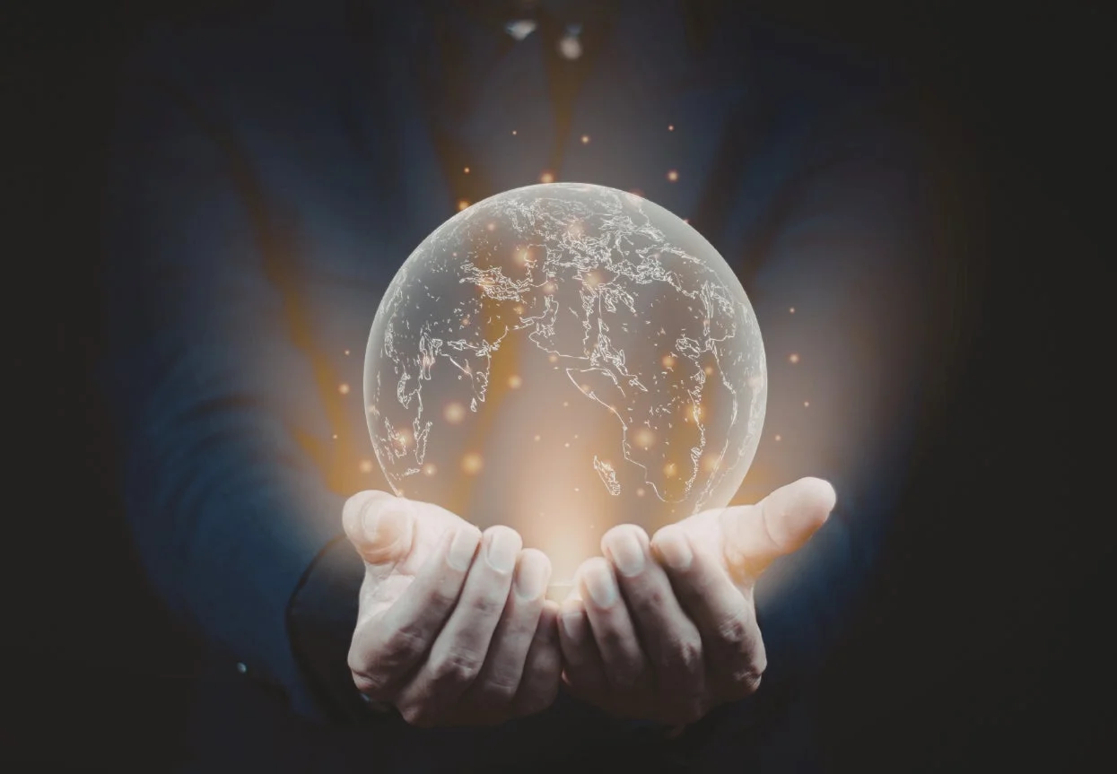 暗い背景の中で、両手が光る地球儀を優しく包み込んでいる様子