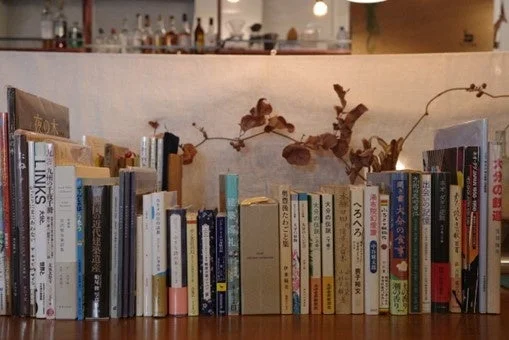 木のカウンターに様々なジャンルの本が並べられた書棚