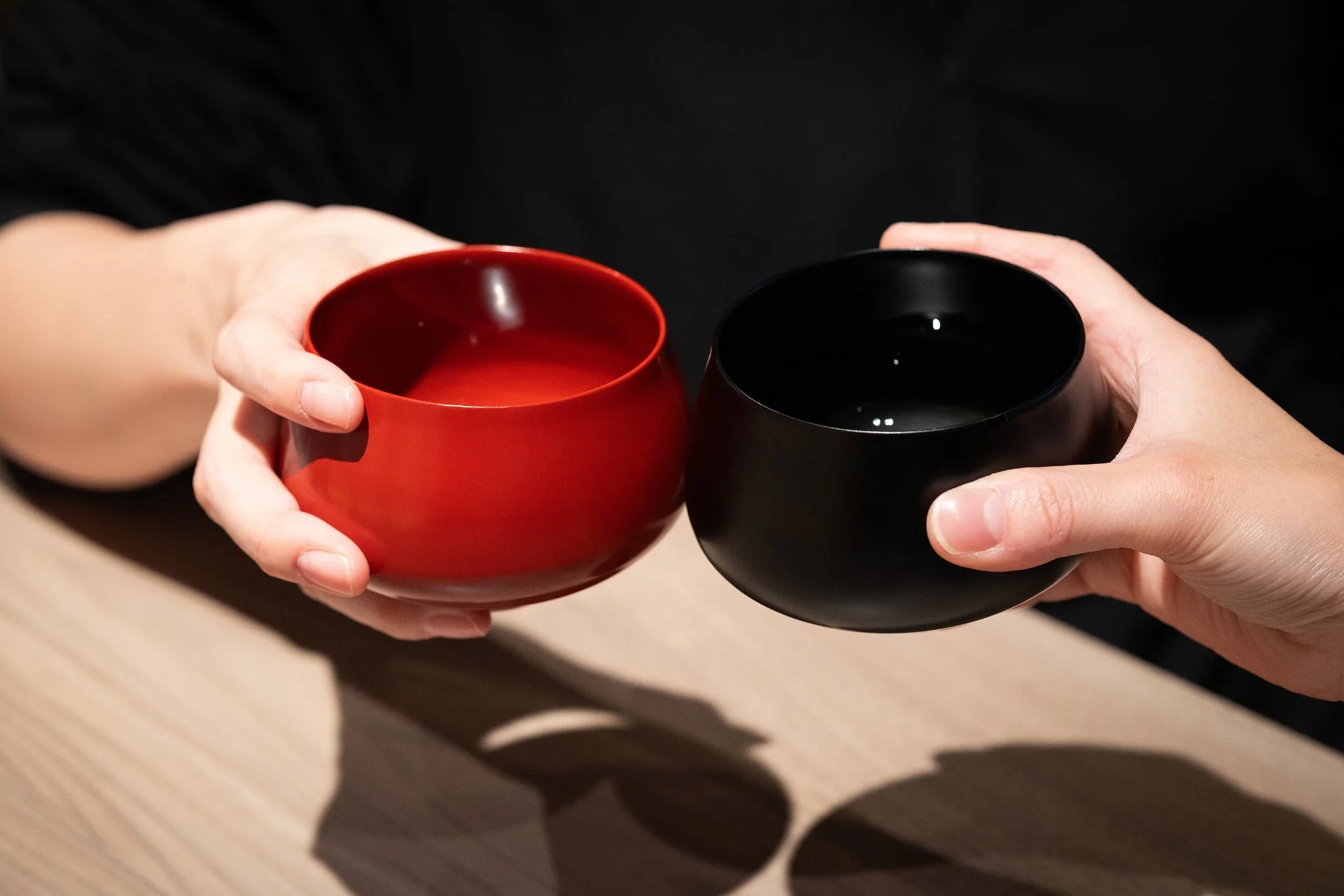 赤い器と黒い器を持ち、乾杯している