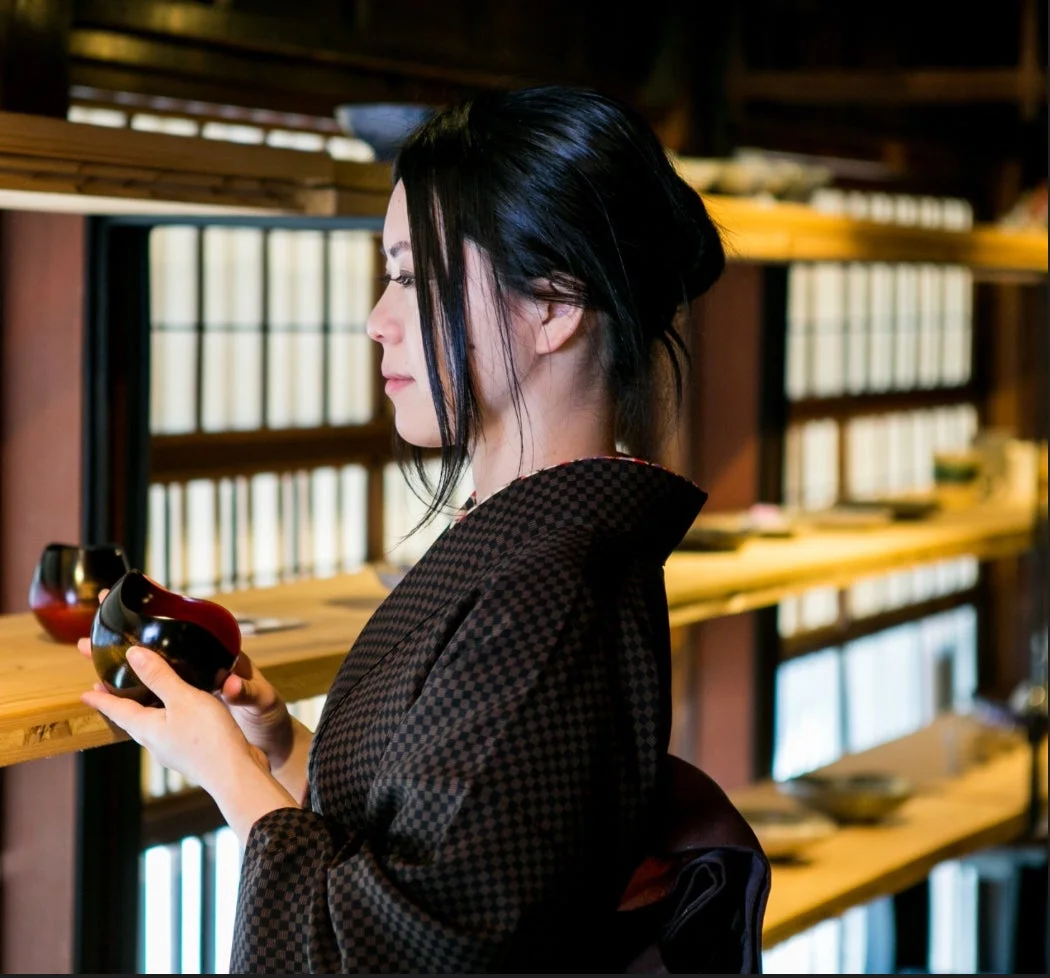 着物を着た日本人女性が、漆塗りのお椀を手にしている