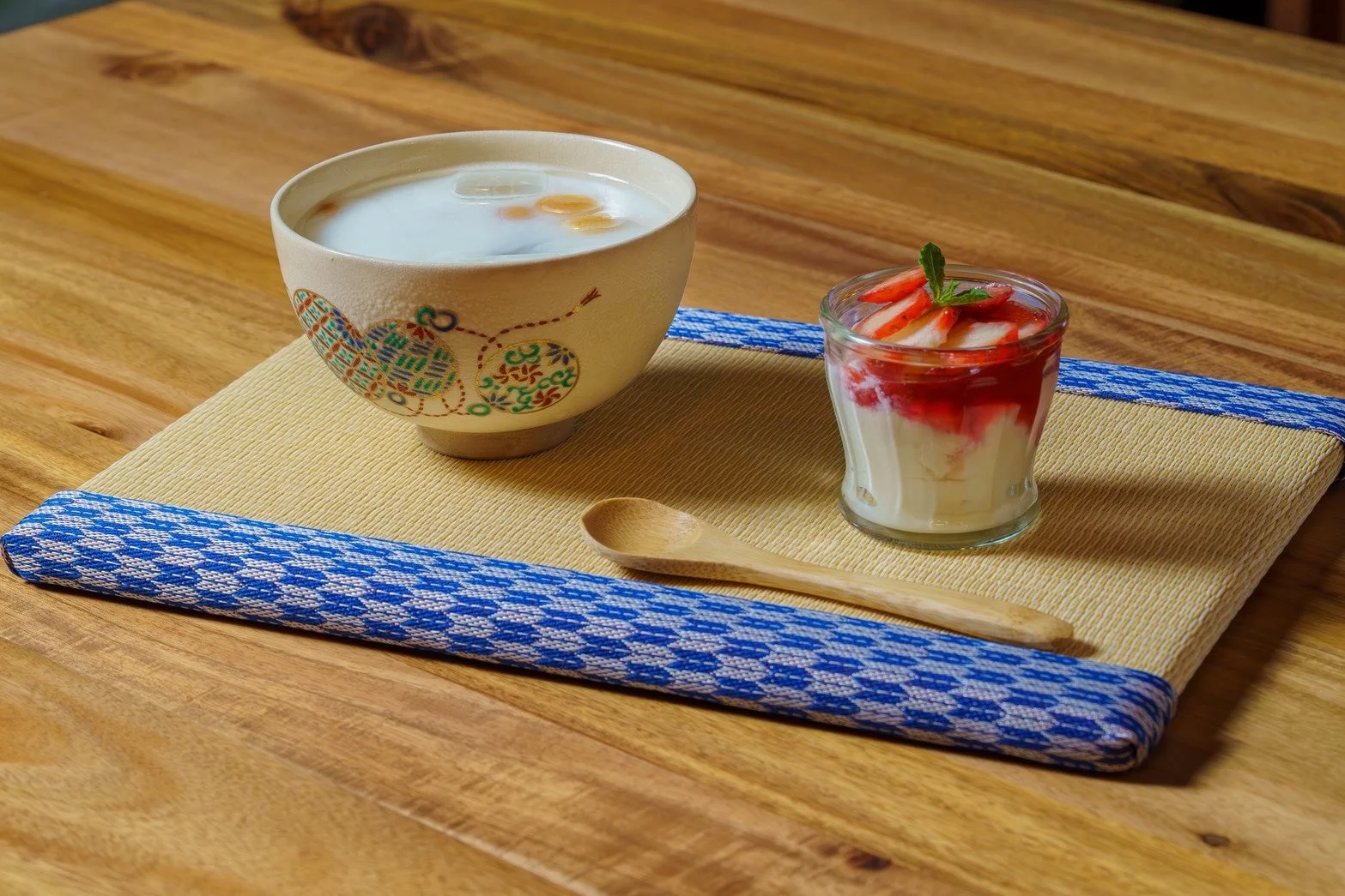 和風の器に入った白い冷たいデザートと、いちごが飾られたグラスデザートが木製のテーブルに置かれている写真です。畳風のランチョンマットと木のスプーンが添えられ、涼しげな夏のデザートタイムを演出しています。