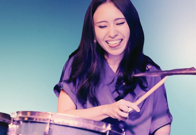 ドラムを叩きながら満面の笑みを浮かべる女性のクローズアップ画像