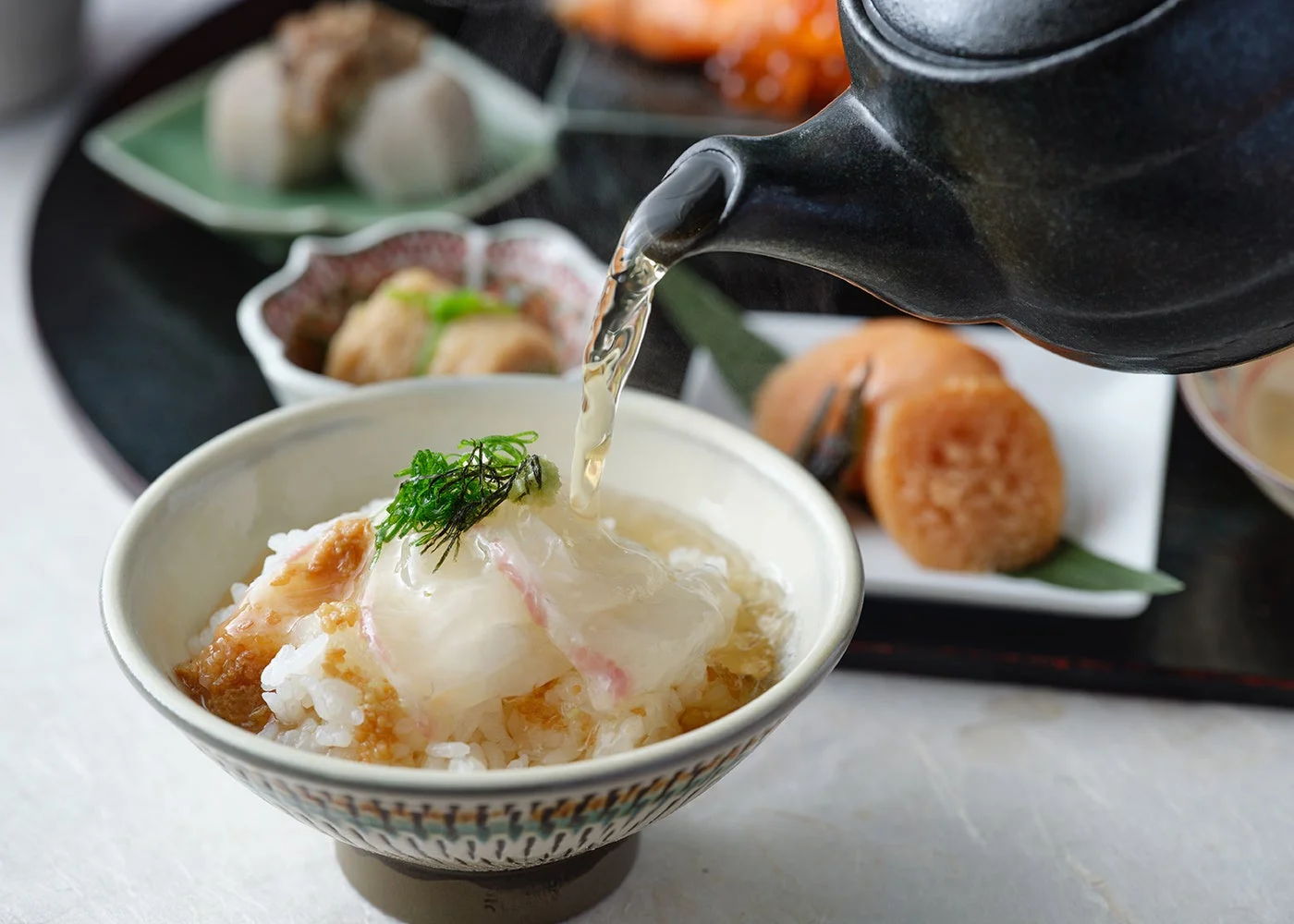 鯛の刺身がのったご飯に温かい出汁が注がれている様子