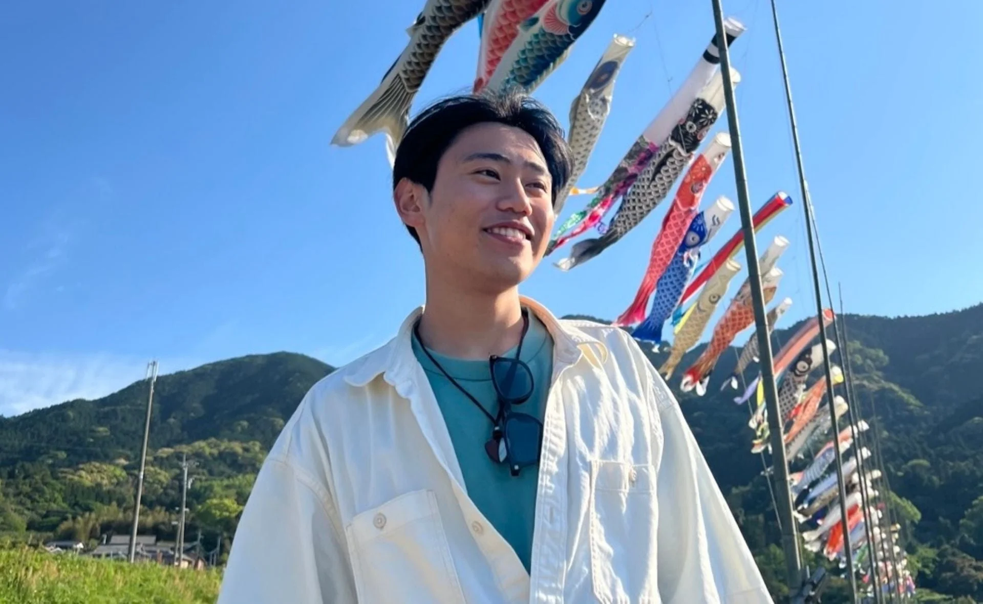 鯉のぼりが泳ぐ中で笑顔を見せる夏志氏
