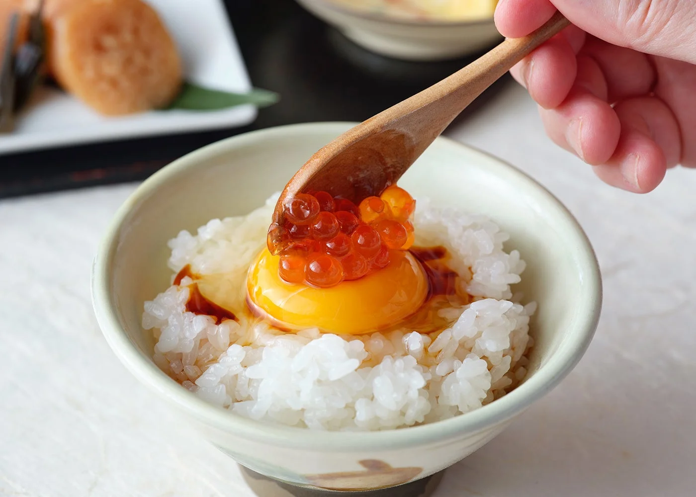 白いご飯の上に生卵の卵黄と輝くいくら