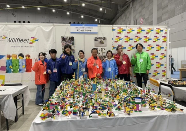 Willfleetのスタッフと参加者がレゴブロックの巨大なジオラマを囲んでいる様子