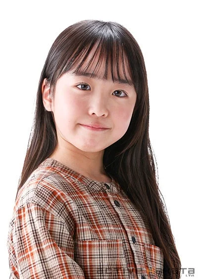 白背景で撮影された、ロングヘアと前髪のあるアジア系の女の子のポートレート写真です。茶色と白のチェック柄のシャツを着て、カメラに向かって優しく微笑んでいます。