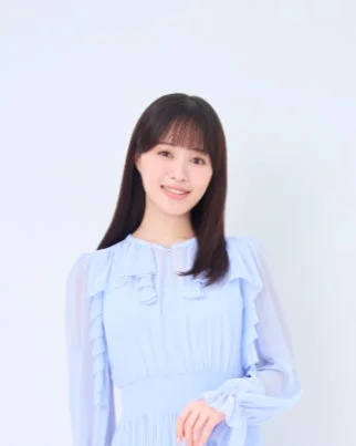 水色のフリル付きドレスを着た若い日本人女性が、笑顔でカメラを見ているポートレート写真