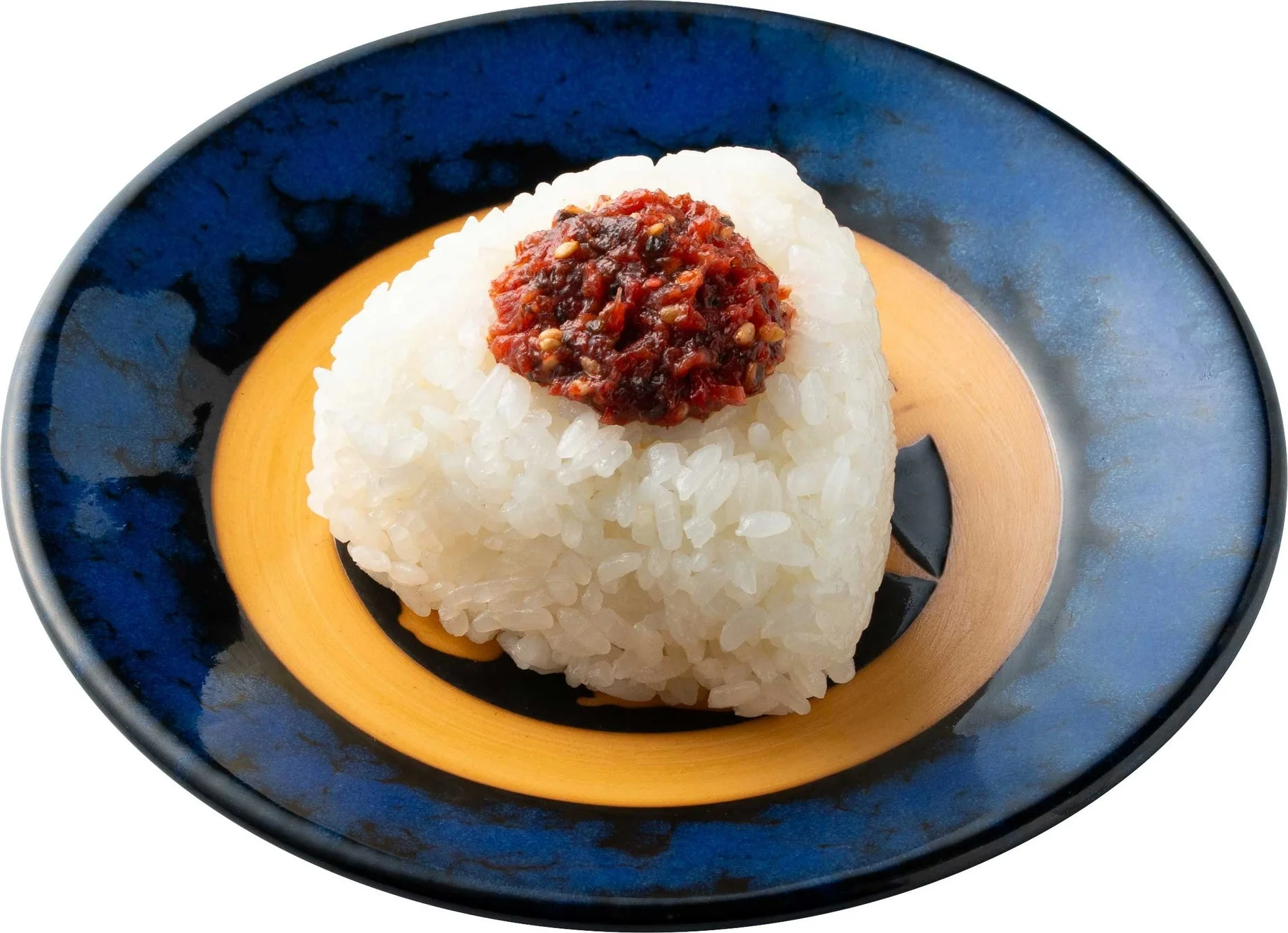 青と黄色の模様が入った皿に盛られた、三角形のおにぎりのクローズアップ画像です。おにぎりの上には、赤くて辛そうな具材がたっぷりと乗っています。