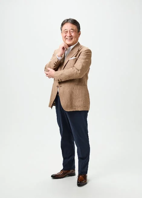 白い背景の前で笑顔を見せる中高年の日本人男性の全身ポートレート