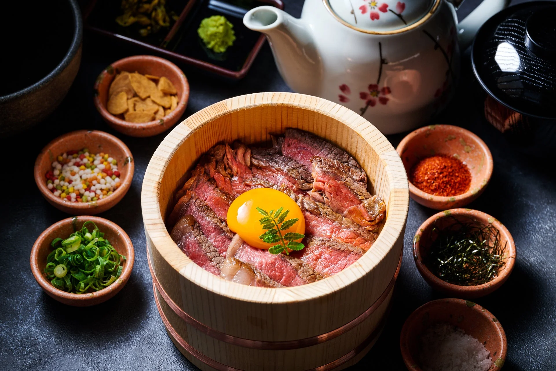 木桶に入ったローストビーフ丼で、中央に卵黄が乗っています