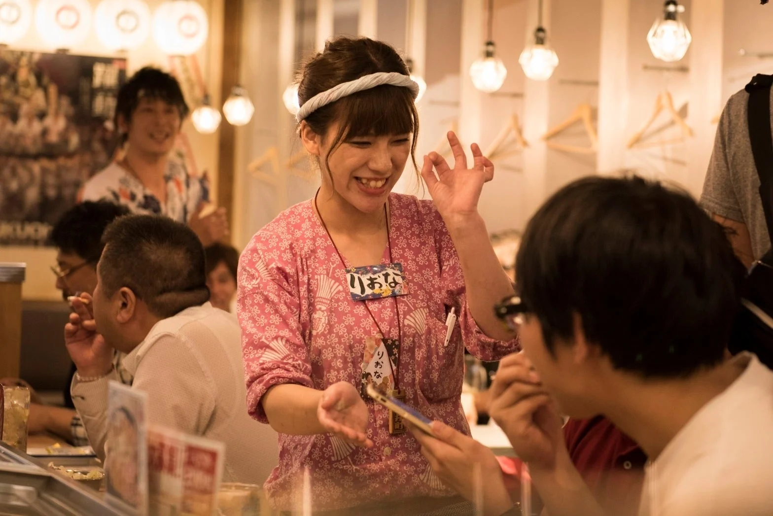 賑やかな飲食店で接客する女性スタッフ