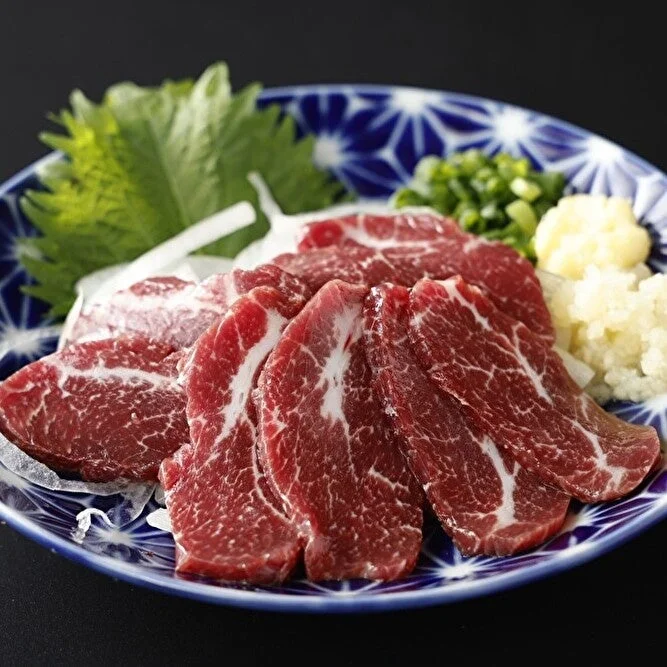 鮮やかな赤色の薄切り生肉と薬味
