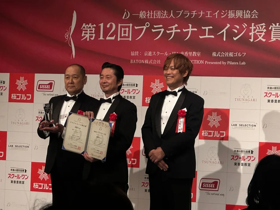 プラチナエイジ授賞式で表彰状とトロフィーを手に記念撮影をする男性3人
