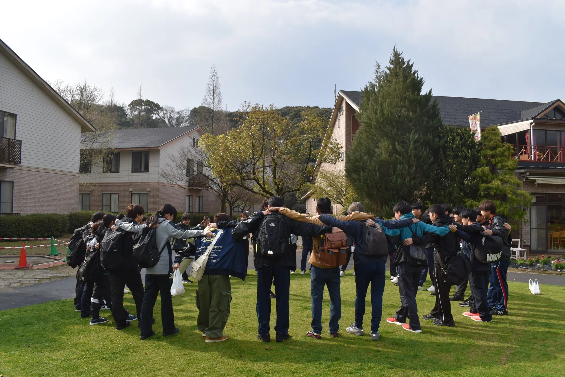 学生、グループ、円陣、肩組み、屋外、芝生、建物、交流、イベント、若者、チームワーク、親睦