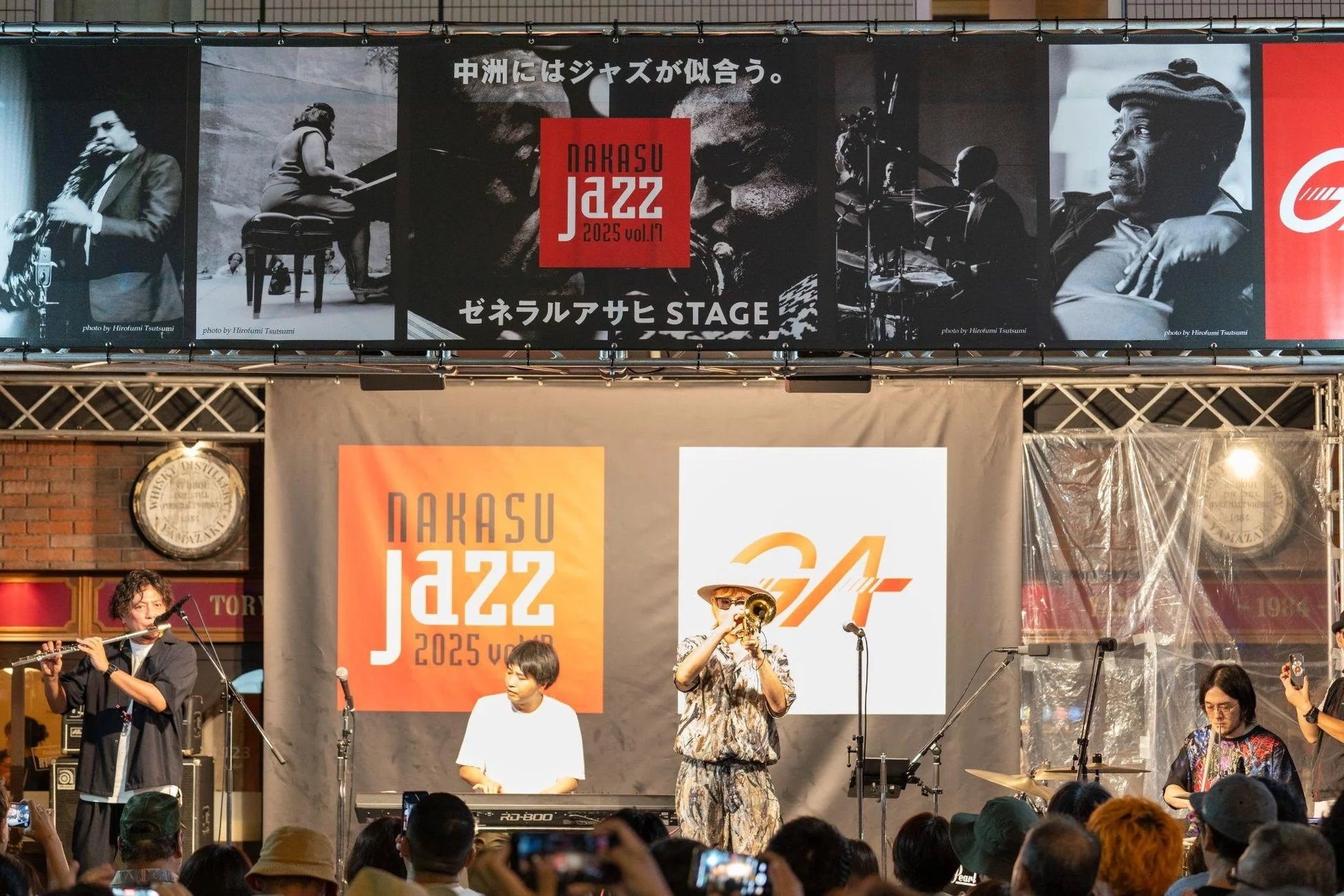 中洲ジャズ2025 vol.17のライブステージで、様々な楽器を演奏するバンドと多くの観客が写っています