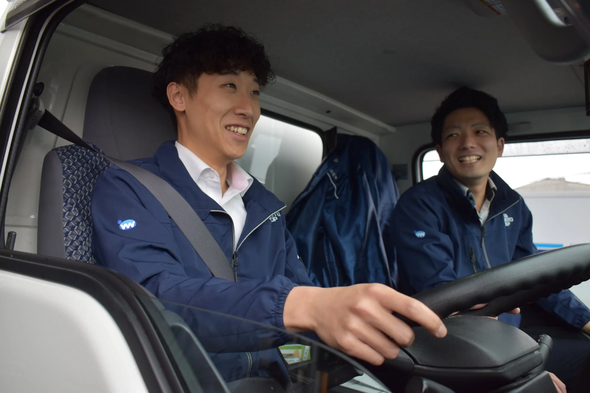 男性、笑顔、車内、運転、同僚、ビジネス、制服、トラック、運送、安全運転、会話、助手席、ドライバー、日本人