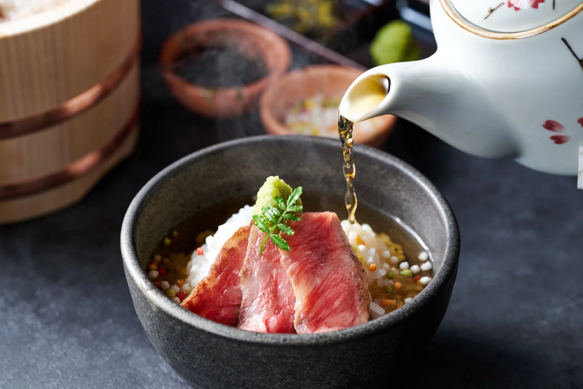 白い急須から出汁が注がれる、牛肉を贅沢に使ったお茶漬けのアップショット