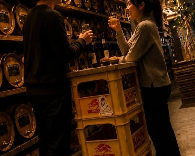 薄暗い店内で、男女のカップルがグラスを手に談笑している様子