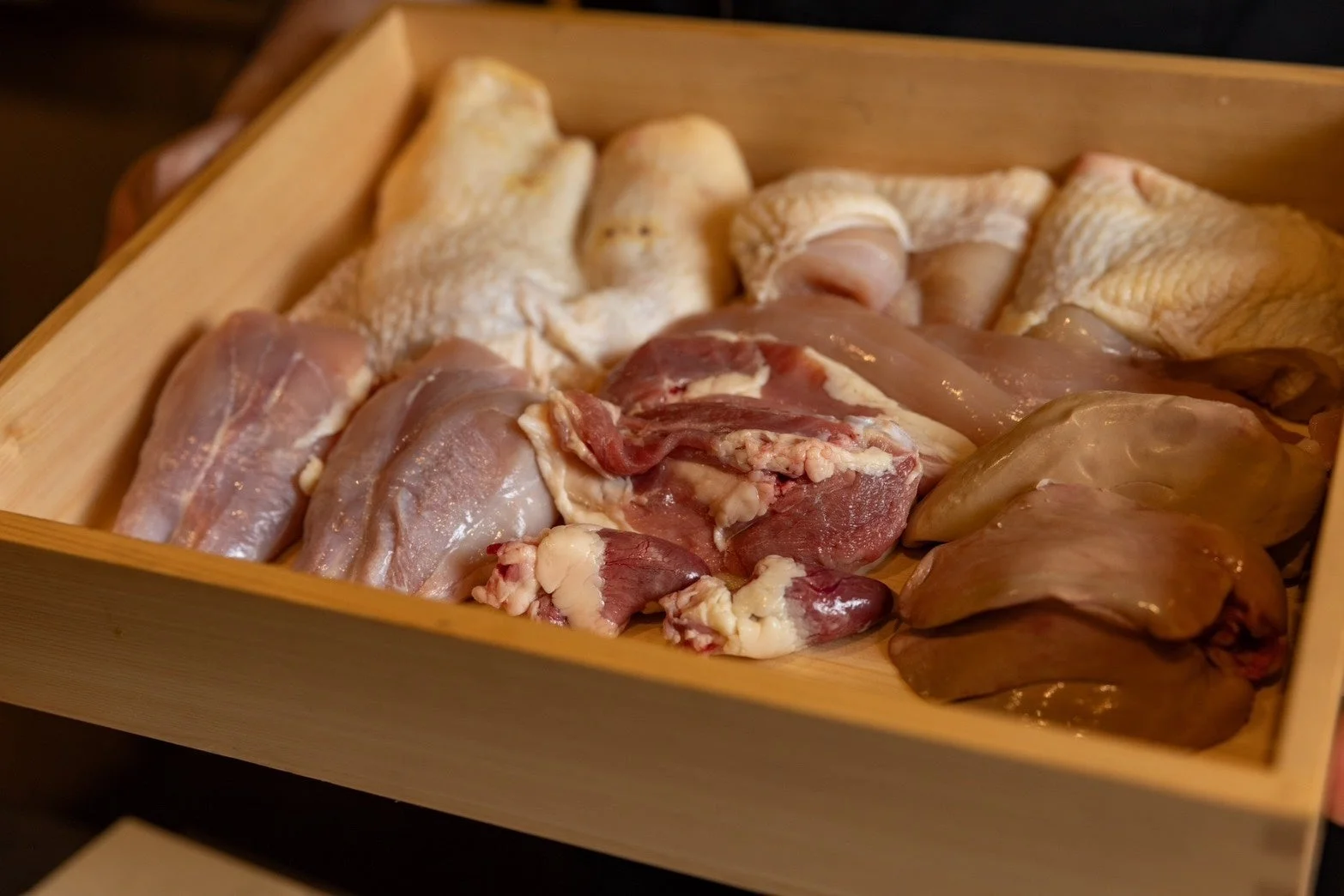 様々な部位の鶏肉が木箱に盛り付けられた画像