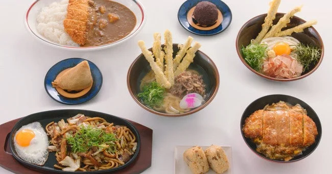 カレーライス、うどん、カツ丼、焼きそばなど、様々な種類の日本食がテーブルに並べられています。