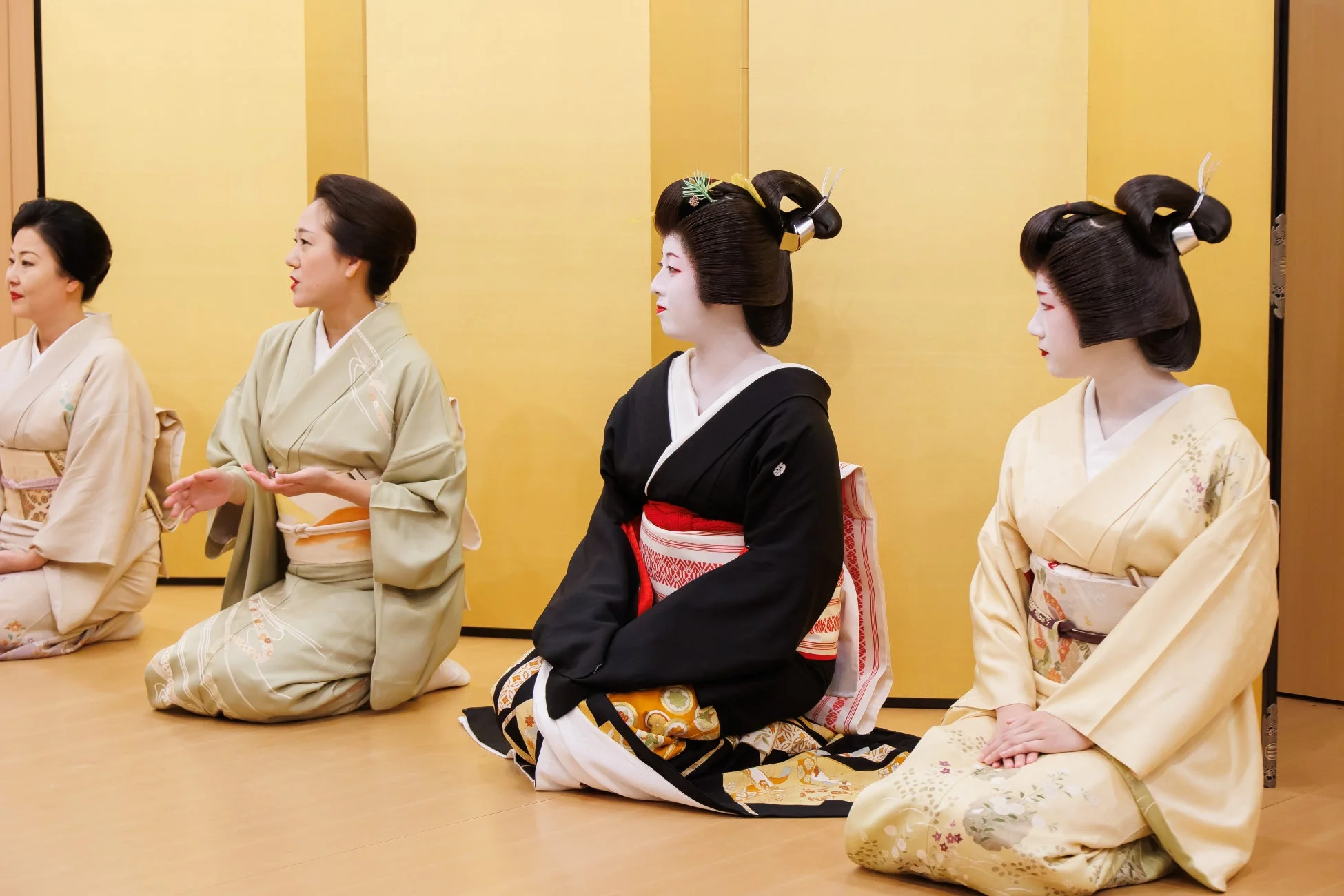 金屏風の前で座る着物姿の女性たち