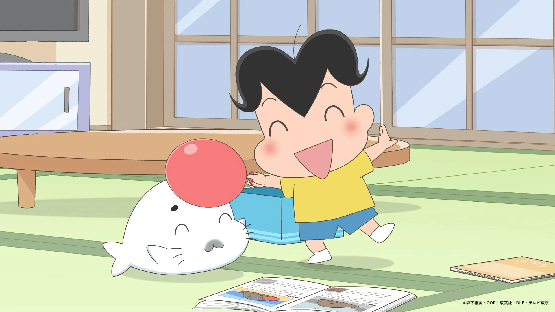笑顔の少年と赤い鼻のアザラシのキャラクターがリビングのような部屋で楽しそうに遊んでいる