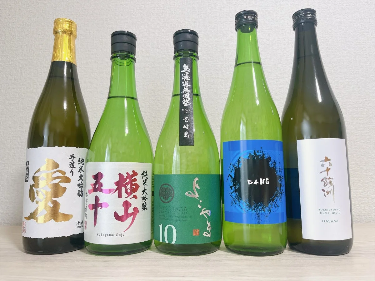 純米大吟醸や純米吟醸を含む5本の日本酒ボトルが並べられた写真。様々な銘柄の日本酒が一度に楽しめるような展示です。