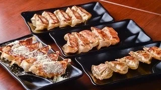 複数の黒い皿に盛り付けられた焼き餃子